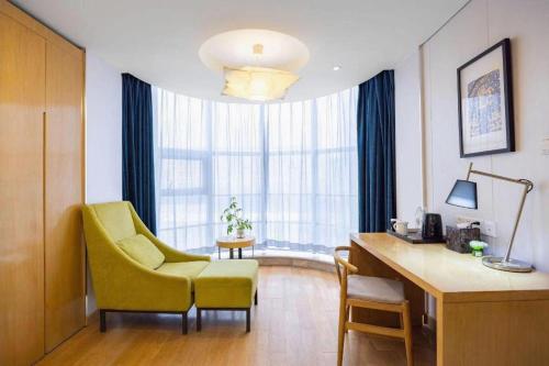 a room with a yellow chair and a desk and a window at Yitel Shenyang Sanhao Street Shengjing Hospital in Shenyang
