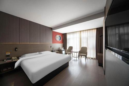 Una habitación de hotel con una gran cama blanca y una mesa. en Jinjiang Inn Select Xi'an Hongmiaopo East Daxing Road, en Xi'an