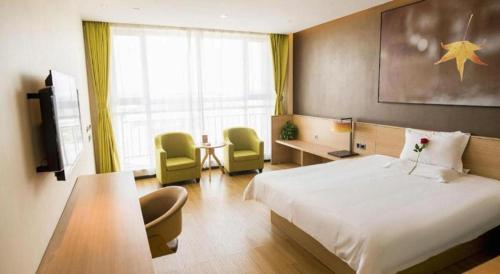 a hotel room with a bed and a table and chairs at IU Hotel Zhangye High-Speed Railway Station in Zhangye
