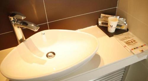 a white sink in a bathroom with a counter at IU Hotel Zhangye High-Speed Railway Station in Zhangye