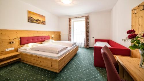 a bedroom with a large bed and a red couch at Hotel Elisabeth in Chienes
