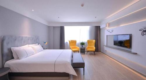 a bedroom with a large bed and two yellow chairs at Magnotel Hotel Jining Yanzhou Metro Station Jiuxianqiao South Road in Jining
