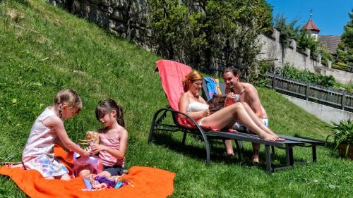 eine Gruppe von Menschen, die auf einer Bank im Gras sitzen in der Unterkunft Hotel Elisabeth in Kiens