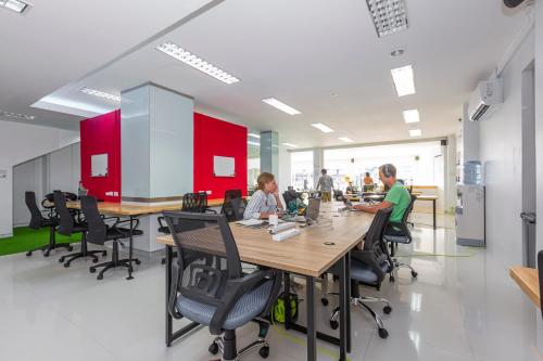 een groep mensen die aan een lange tafel in een kantoor zitten bij Banana Bunkhouse Hostel in Rawai Beach