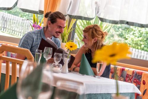 a man and woman sitting at a table with wine glasses at Hotel Elisabeth in Chienes