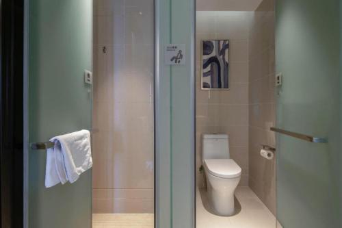 a bathroom with a toilet and a glass shower door at Echarm Hotel Nanning Chaoyang Square River View in Nanning