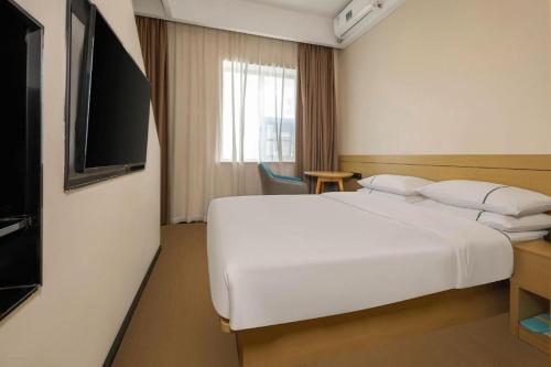 a hotel room with a white bed and a television at City Comfort Inn Liuzhou Wuling Liutai Road in Liuzhou