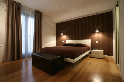 um quarto com uma cama e um repousa-pés preto em Belmonte Hotel, Dependance Alba Palace Hotel em Favara