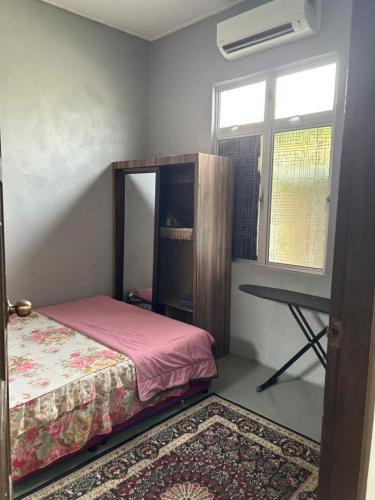 a bedroom with a bed and a window and a desk at CILI PADI GUESTHOUSE in Kota Bharu