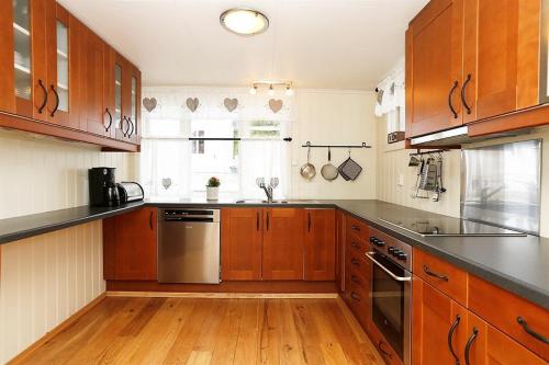 a kitchen with wooden cabinets and stainless steel appliances at Mandal Privat Romutleie in Mandal