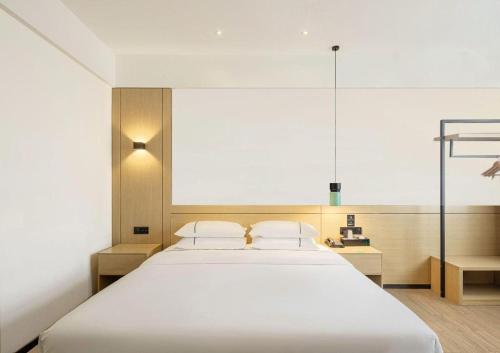 een slaapkamer met een groot wit bed met twee kussens bij City Comfort Inn Zhoukou City Chuanhui District Huanghe Road in Zhoukou