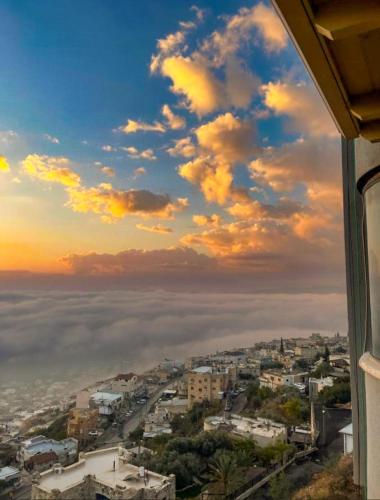 a view from a window of a city with clouds at Galilee Hills - Resort & Suites in Maghār
