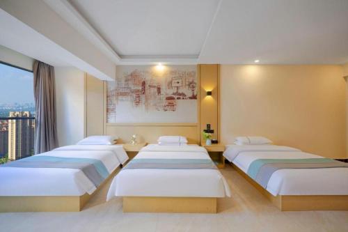 a hotel room with three beds and a window at City Comfort Inn Kunming High Speed Railway South Station Yongxin Harvard in Kunming