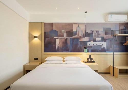 a bedroom with a white bed with a painting on the wall at City Comfort Inn Changsha South Railyway Station West Square in Changsha
