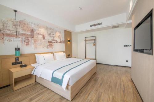 a bedroom with a large bed and a flat screen tv at City Comfort Inn Changsha South Railyway Station West Square in Changsha
