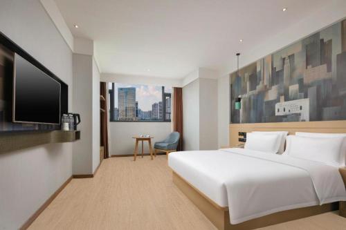 a bedroom with a white bed and a flat screen tv at City Comfort Inn Changsha South Railyway Station West Square in Changsha
