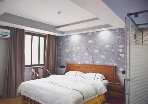 a bedroom with a bed with a floral wall at Pai Hotel Huai'an Lianshui Huaipu Bei Road in Lianshui