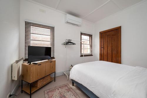 a bedroom with a bed and a flat screen tv at Deco Days - Prahran in Melbourne