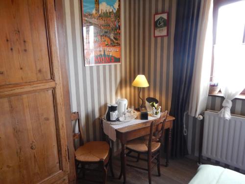 Zimmer mit einem Tisch mit Stühlen und einer Lampe in der Unterkunft B&B La Chrysalide in Mons