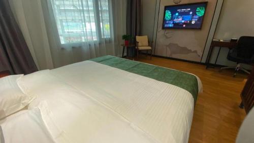 a bedroom with a white bed and a flat screen tv at GreenTree Inn Express Datong High-Speed Railway Station Wanda Plaza Fangte in Datong