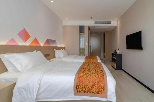 a bedroom with a large white bed and a flat screen tv at Borrman Hotel Hefei Yaohai Wanda Linquan East Road in Hefei