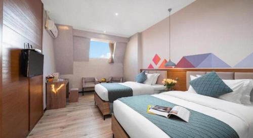 a hotel room with two beds and a television at Borrman Hotel Yuxi Yuxing Road in Yuxi