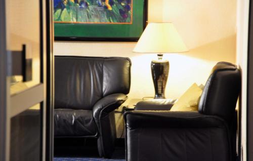 two black leather chairs and a lamp in a hotel room at Hotel Pegasus in Munich
