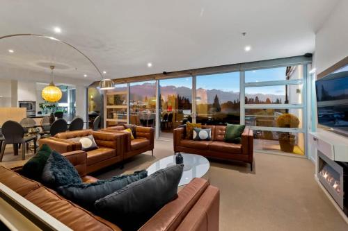 a living room with leather couches and a tv at Taimana Queenstown in Queenstown