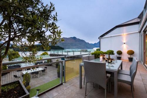 a balcony with a table and chairs and a view of the water at Taimana Queenstown in Queenstown