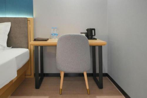 a desk with a chair next to a bed at Green Tree Inn Urumqi San'gong Metro Station Exit in Ürümqi