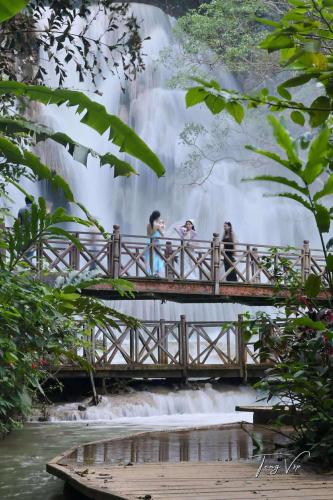 a group of people walking over a bridge over a waterfall at Luang Prabang Golden Lotus Villa River View in Luang Prabang