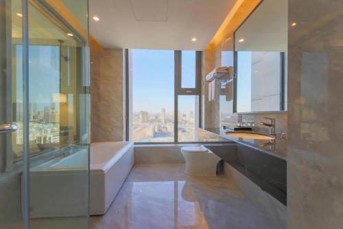 a bathroom with a tub and a toilet and a window at Venus Royal Hotel Ordos Yijinhuoluo Banner Olympic in Ordos