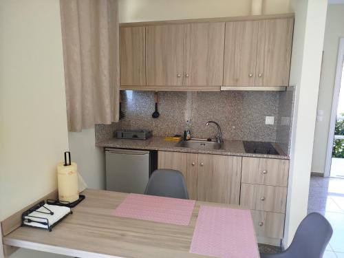 a kitchen with wooden cabinets and a table with chairs at Nereids Apartments-Pronoe in Petalidhion