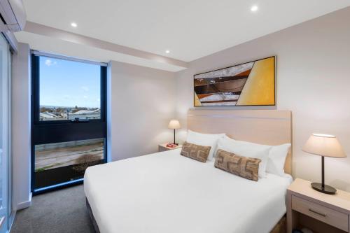 a bedroom with a large white bed and a large window at iStay Precinct Adelaide in Adelaide