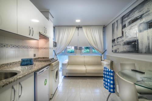 uma cozinha com um lavatório e um sofá num quarto em Apartamentos Las Brisas em Santander