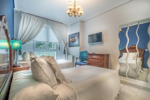 a bedroom with a large bed and a tv at Apartamentos Las Brisas in Santander