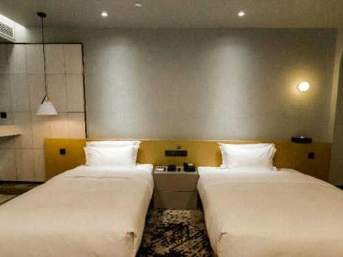 two beds sitting next to each other in a room at Borrman Hotel Jining High-tech Huangtun in Jining