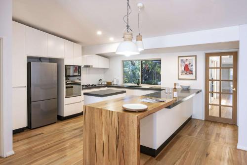 a kitchen with white cabinets and a wooden island at Peaceful Peron - outdoor pool, close to beach in Dunsborough