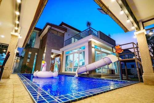 a large swimming pool with a water slide in front of a house at Cozy beachside pool villa in Ban Rong Po