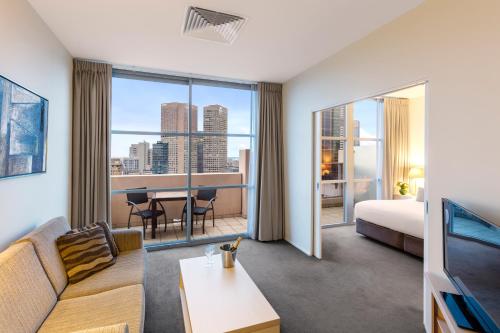 a hotel room with a couch and a room with a view at Oaks Melbourne on Lonsdale Suites in Melbourne