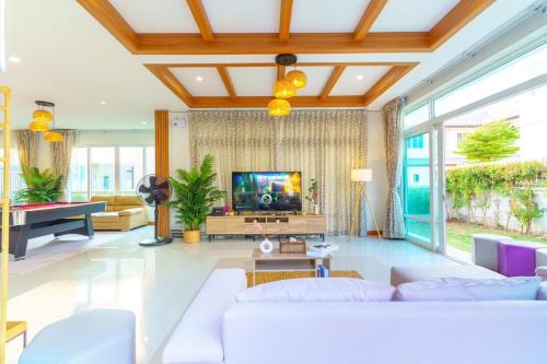 a living room with white furniture and a flat screen tv at Cozy beachside pool villa in Ban Rong Po