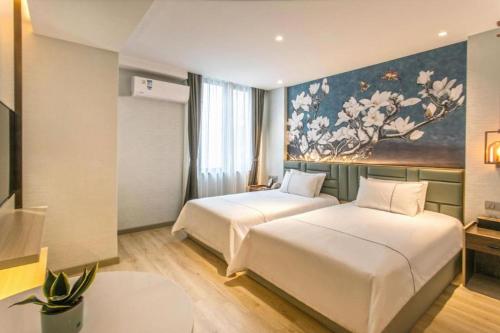 two beds in a hotel room with a painting on the wall at Magnotel Hotel Suzhou Shiquan Street Wangshiyuan in Suzhou