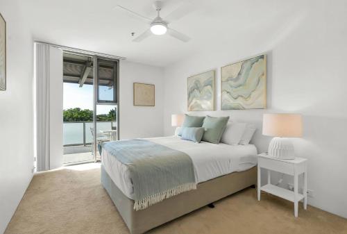 a white bedroom with a bed and a window at Cairns Coastal Charmer - Your Waterfront Sanctuary in Cairns