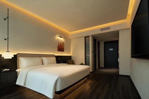 a bedroom with a large white bed and a television at Yomanju International Hotel -Guangzhou Tower Zhujiang NewTown Sports West Road Branch &地铁站- Canton Fair Exclusive Rate in Guangzhou