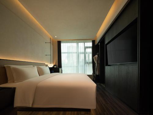 a bedroom with a white bed and a flat screen tv at Yomanju International Hotel -Guangzhou Tower Zhujiang NewTown Sports West Road Branch &地铁站- Canton Fair Exclusive Rate in Guangzhou