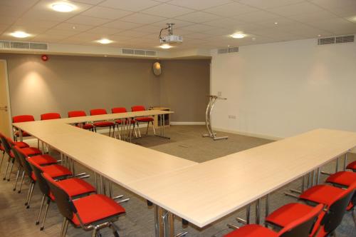 a conference room with a long table and red chairs at Kings Court Hotel in Stratford-upon-Avon