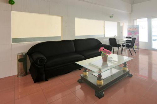 a black couch sitting in a living room with a table at Hotel O Makassar near Pantai Losari formerly Hotel Tiara Sari in Makassar