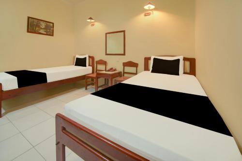 a room with two beds and chairs in it at Hotel O Makassar near Pantai Losari formerly Hotel Tiara Sari in Makassar