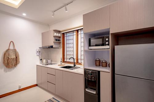 a kitchen with white cabinets and a refrigerator at Emerald Pura 2BR Villa - Private & Peaceful in Ungasan