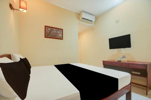 a hotel room with a bed and a television at Hotel O Makassar near Pantai Losari formerly Hotel Tiara Sari in Makassar